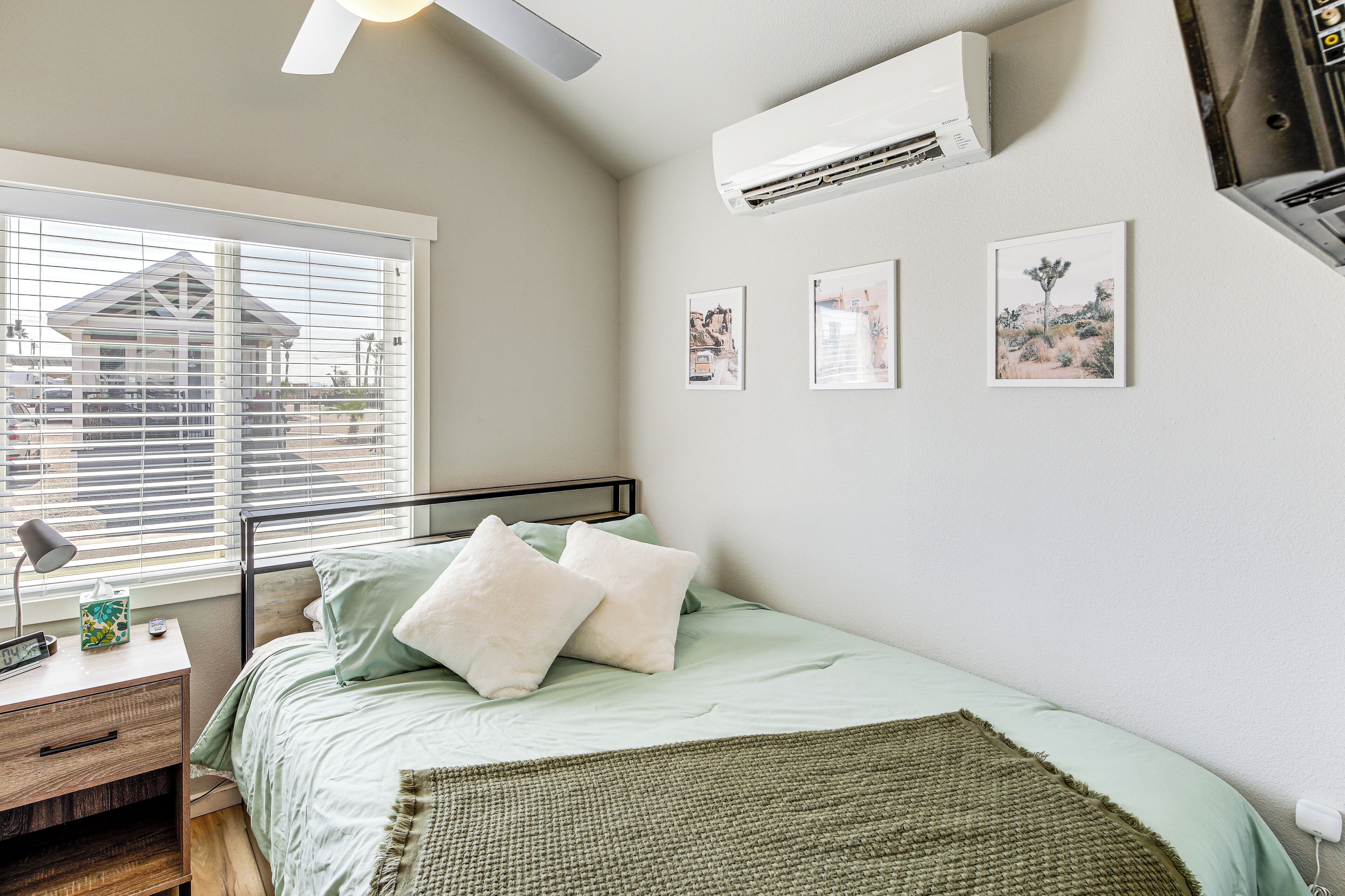 Ein Schlafzimmer mit einem Bett, Nachttisch, Lampe und Klimaanlage.