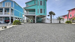 A two-story building with a covered entrance and a gravel driveway. - Large-group Getaway - Beachfront Home w/ Pool! (Supply)