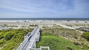 A beach with a wooden boardwalk, sandy beach, and ocean view. - Large-group Getaway - Beachfront Home w/ Pool! (Supply)