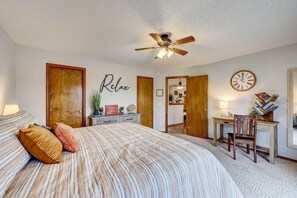 A bedroom with a bed, a desk, a chair, a ceiling fan, and a wall clock. - Holiday Island Vacation Rental w/ 2 Balconies (Eureka Springs)
