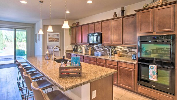 Una cocina moderna con encimeras de granito, electrodomésticos de acero inoxidable y armarios de madera.