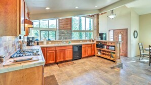 A spacious kitchen with wooden cabinets, a built-in dishwasher, and a wine rack. - Mountain-view Deck: Bright Sedona Home (Sedona)