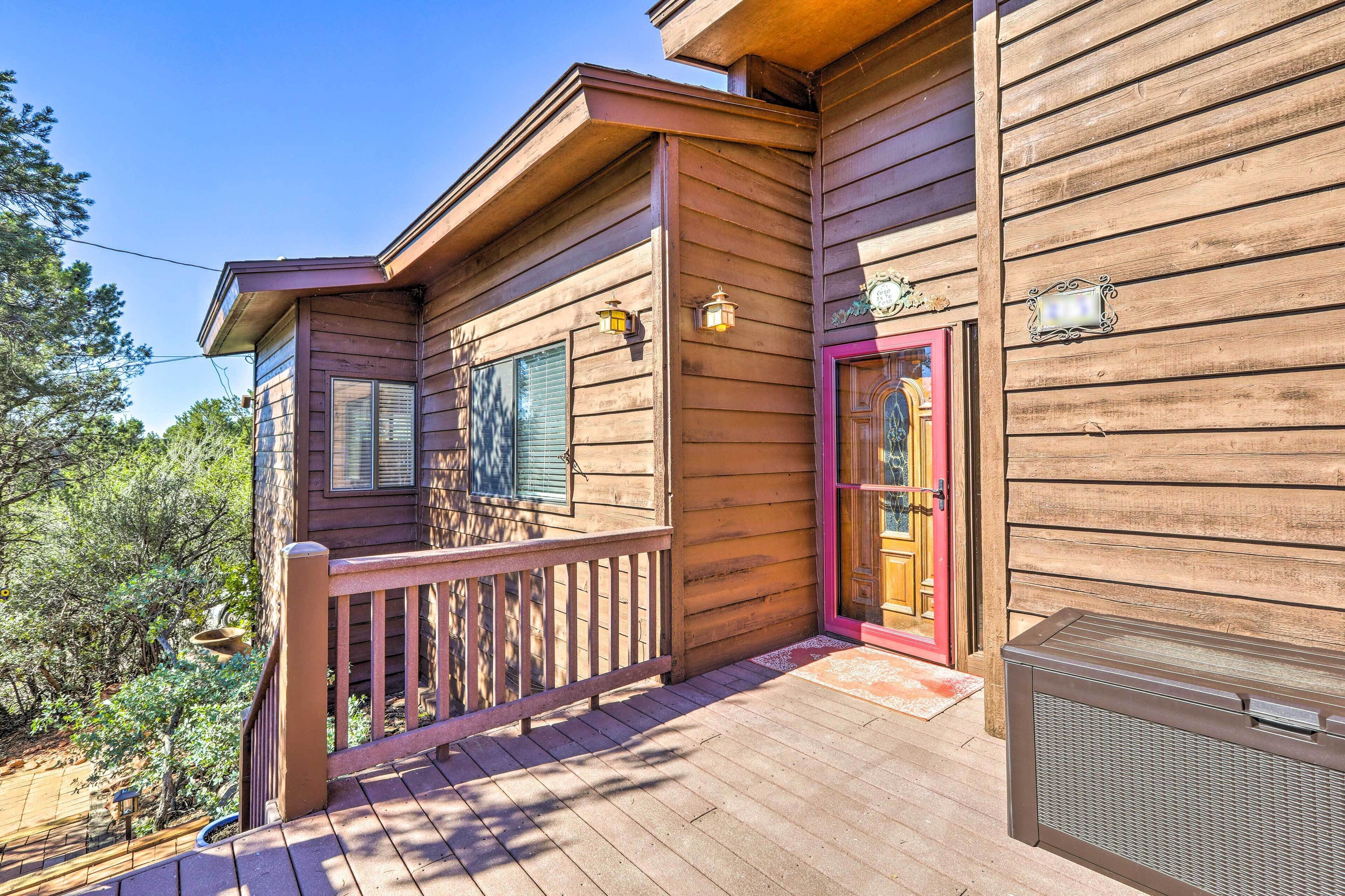 A wooden cabin with a balcony, a red door, and a small porch area.