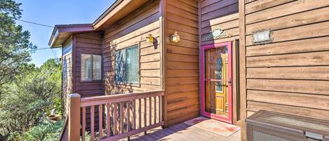 A wooden cabin with a balcony, a red door, and a small porch area.