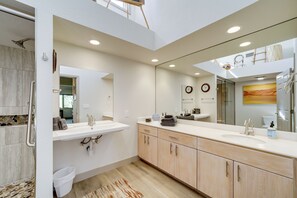 A modern bathroom with a large mirror, dual sinks, and a shower area.