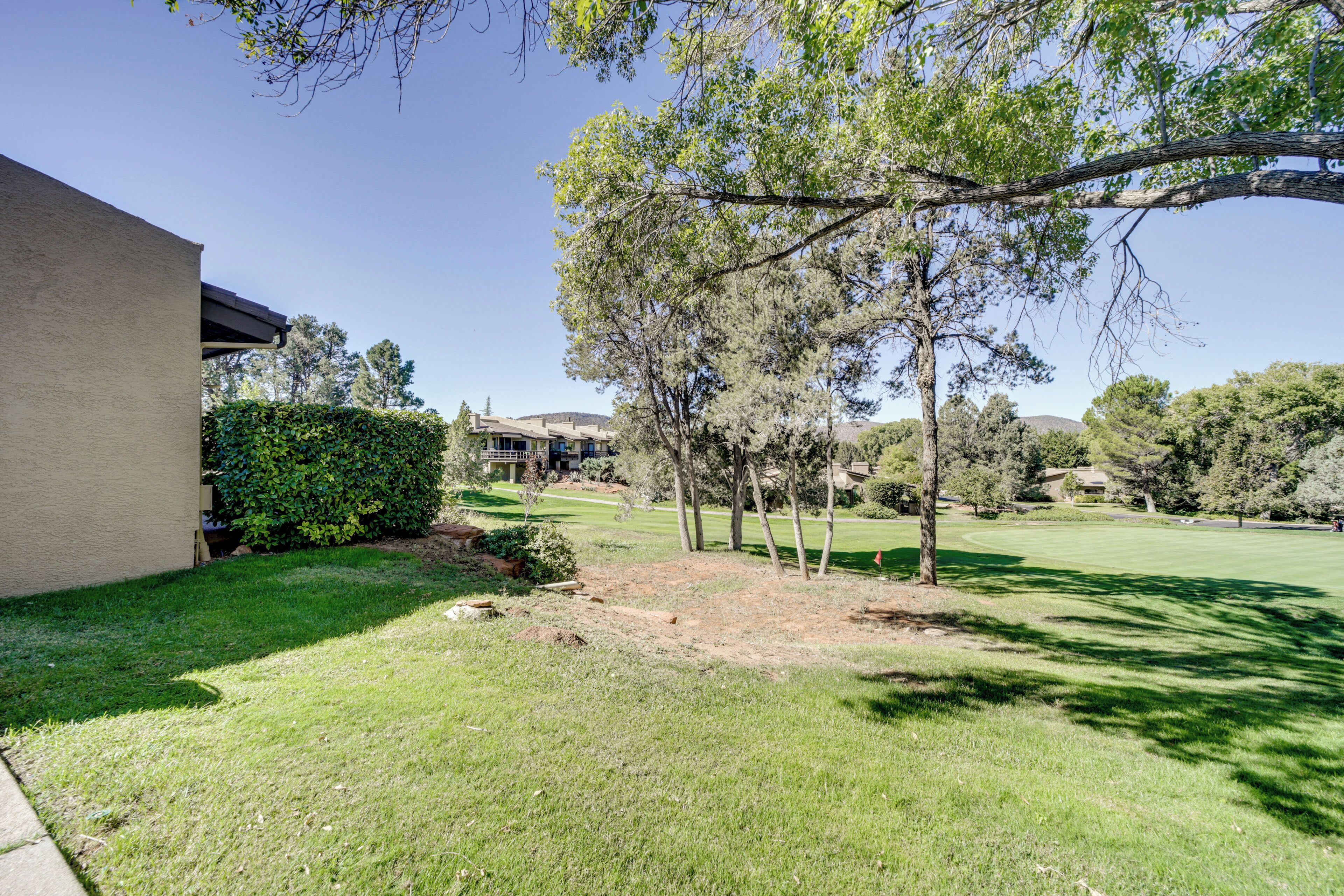 A residential property with a well-maintained lawn, mature trees, and a building with a flat roof.