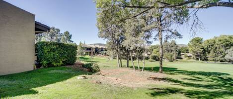 A residential property with a well-maintained lawn, mature trees, and a building with a flat roof.