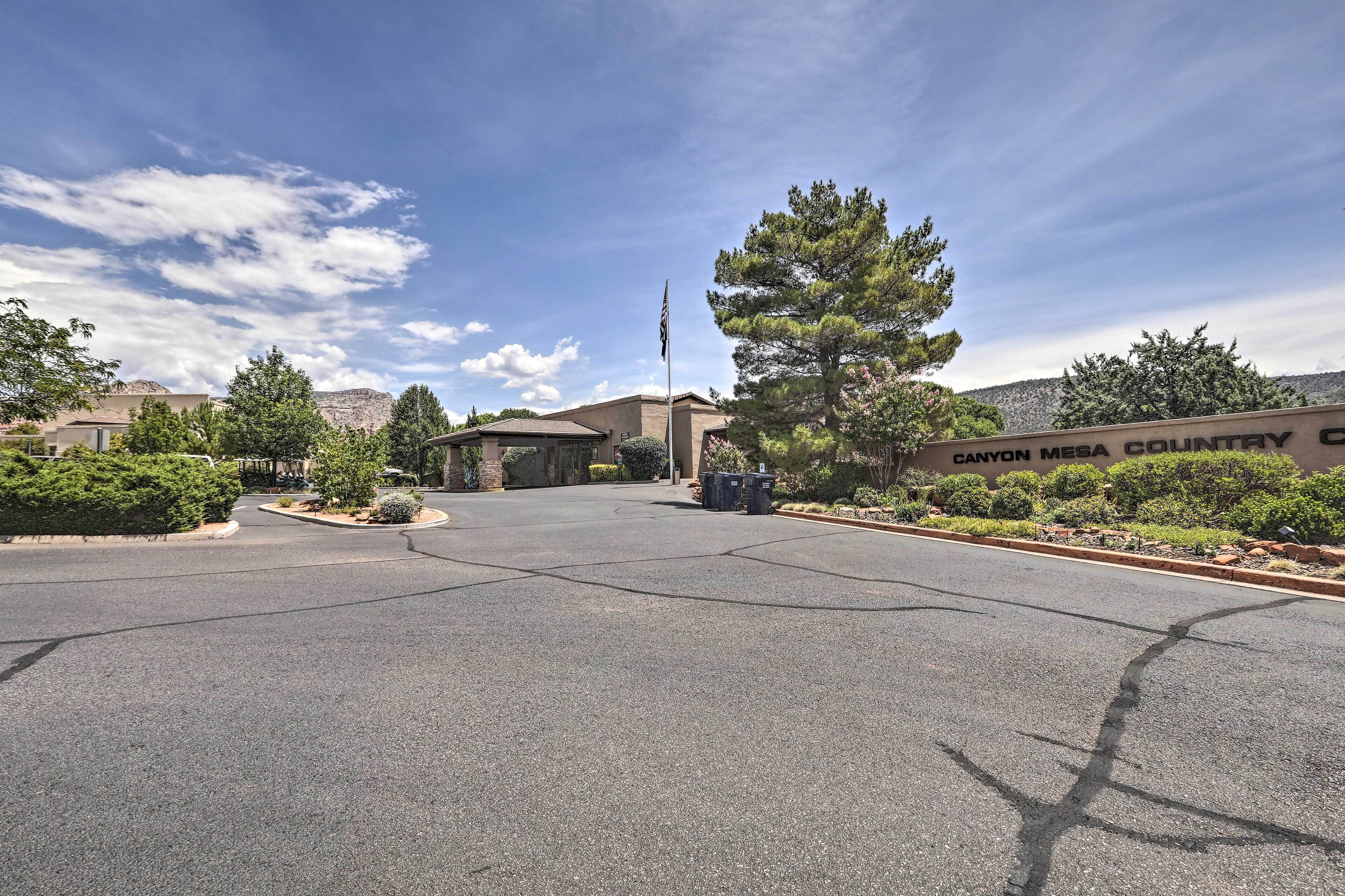A parking lot with a building entrance, a flagpole, and a sign reading "Canyon Mesa Country Club".