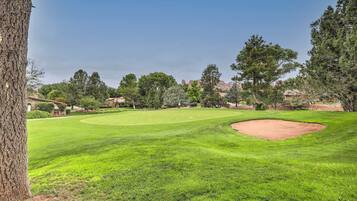A well-maintained golf course with a clear fairway, sand bunkers, and a variety of trees.