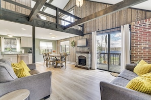 A spacious living area with a fireplace, wooden beams, and a dining area with a table and chairs.