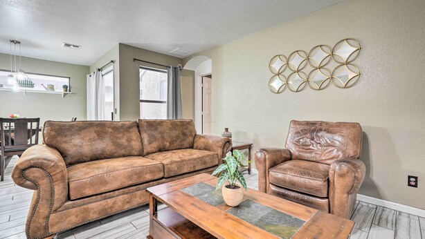 A living room with a brown leather sofa, a wooden coffee table, and a brown leather armchair. There is a potted plant on the coffee table. - 2 Mi to Sports Complex: Peoria Home w/ Patio! (Peoria)
