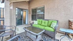 A covered patio area with a green cushioned sofa, wicker chairs, and a glass-top table. - 2 Mi to Sports Complex: Peoria Home w/ Patio! (Peoria)
