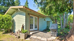 A small, single-story house with a covered porch and a barbecue grill in the yard. - Quaint Riverside Reprieve w/ Kayaks + Floats! (Brookings)