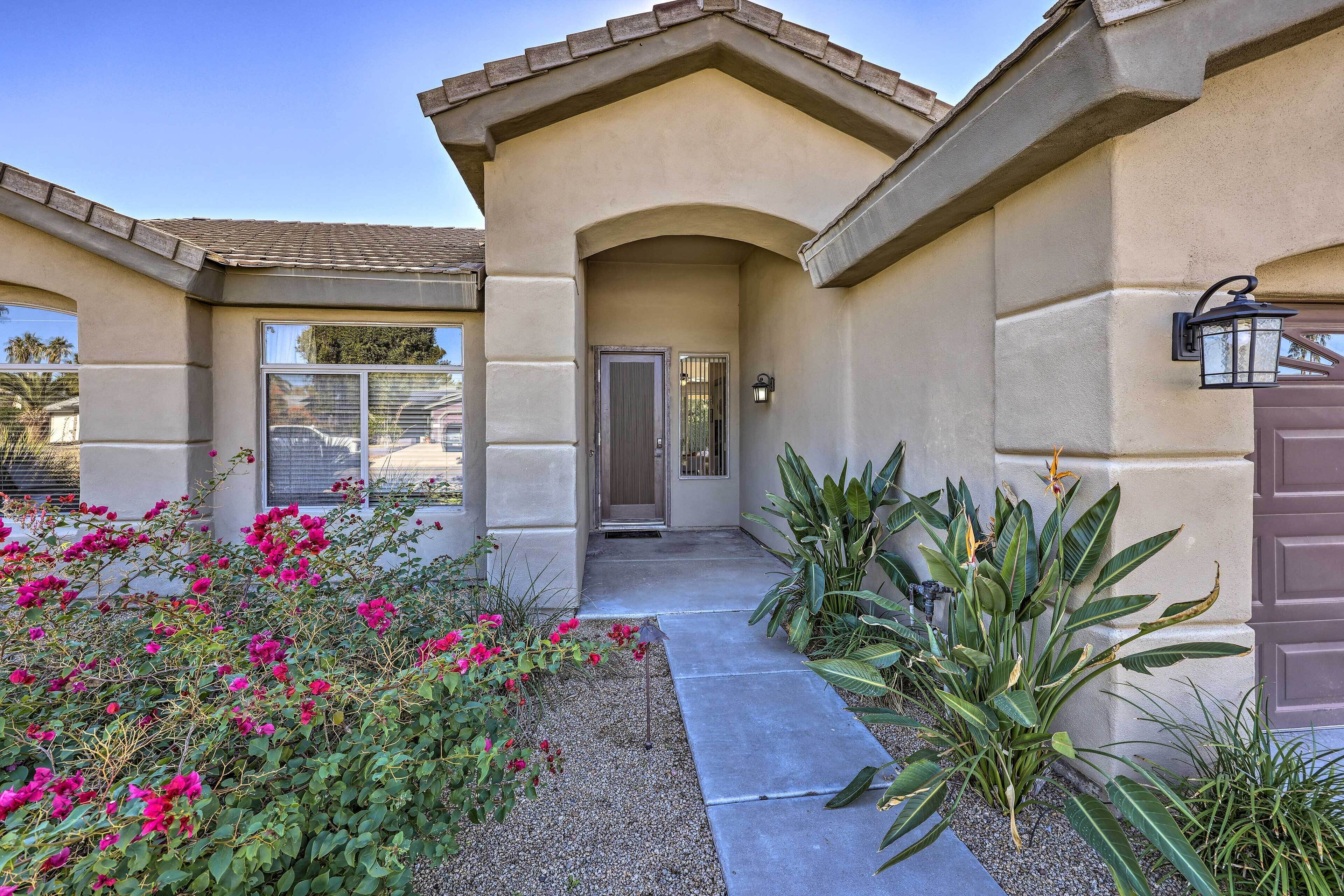 A house with a beige exterior, a front door, and a pathway leading to the entrance.