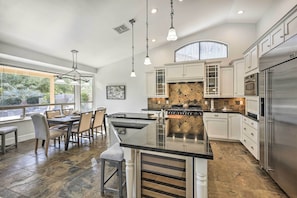 A modern kitchen with a central island, stainless steel appliances, and a dining area with a view of the outdoors. - Airy Scottsdale Home: Pool, Putting Green & Grill! (Scottsdale)