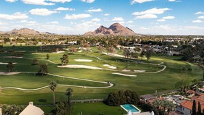 Un parcours de golf avec une montagne en arrière-plan, entouré de zones résidentielles.