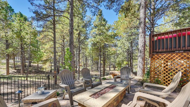 An outdoor patio with a stone fire pit, wooden chairs, and a table. - Flagstaff Hideaway: Private Hot Tub, 4 Mi to Dtwn! (Flagstaff)