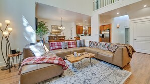 A spacious living room with a sectional sofa, a coffee table, and a rug. There is a staircase leading to an upper level. - Flagstaff Hideaway: Private Hot Tub, 4 Mi to Dtwn! (Flagstaff)