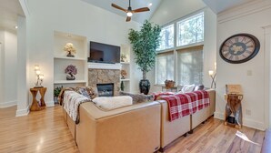 A spacious living room with a fireplace, a large clock, and a ceiling fan. - Flagstaff Hideaway: Private Hot Tub, 4 Mi to Dtwn! (Flagstaff)
