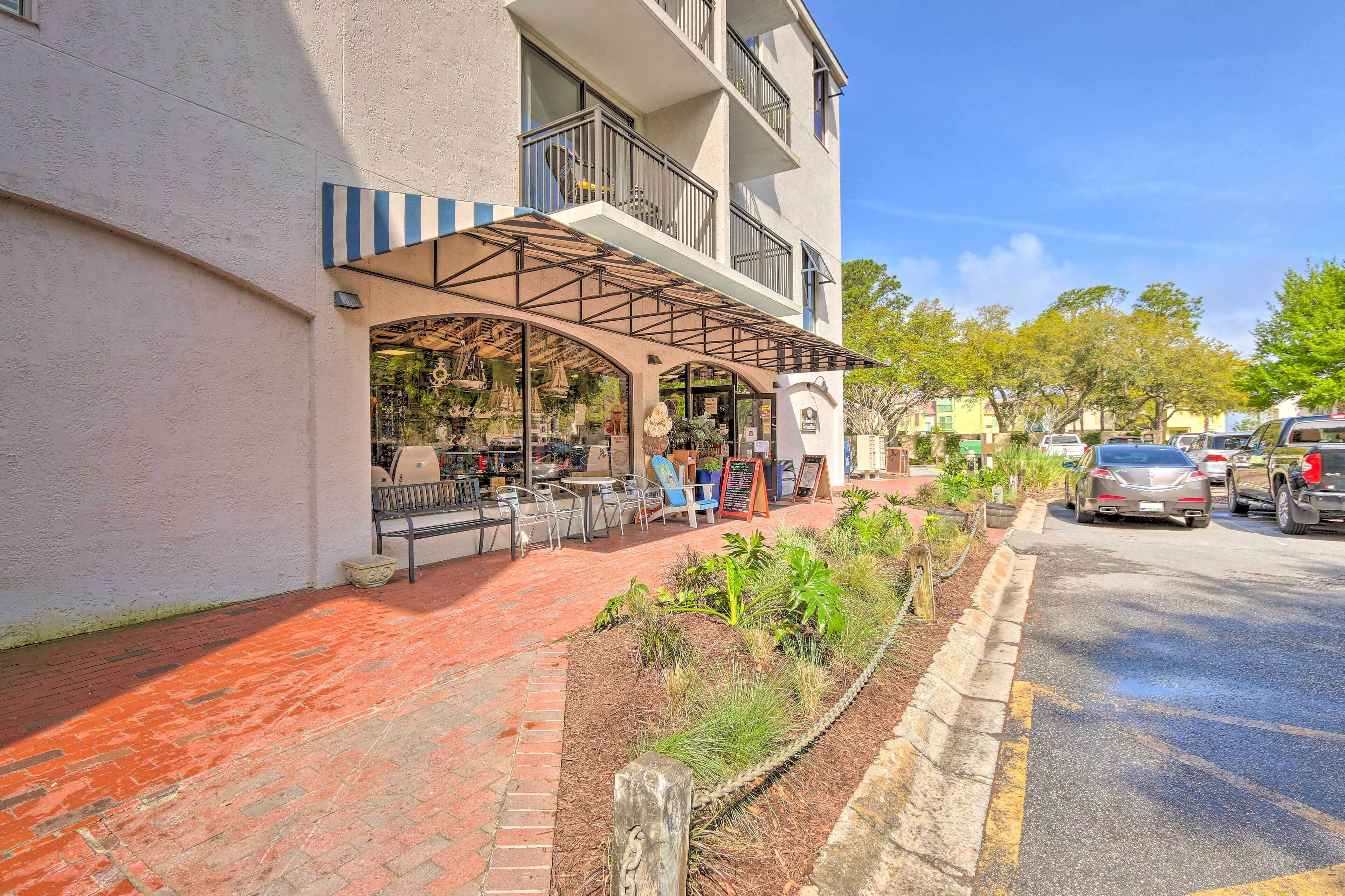 A building with a covered outdoor seating area, a brick pathway, and a street with parked cars.