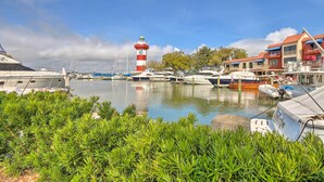 Ein Yachthafen mit vertäuten Booten, einem Leuchtturm und einem Gebäude mit Balkonen.