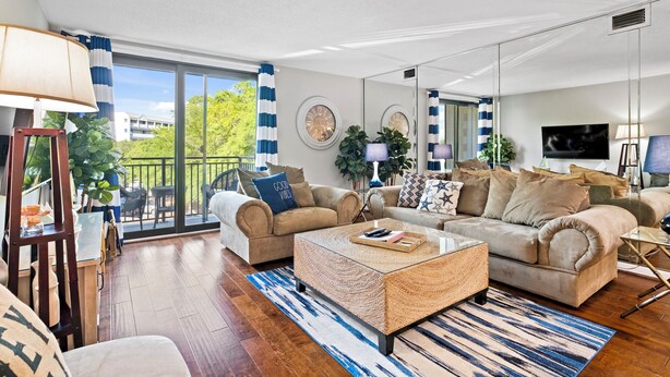 Ein geräumiges Wohnzimmer mit einer großen Couch, einem Couchtisch und einem Balkon mit Blick auf Grünflächen.