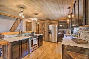 A modern kitchen with wooden accents, stainless steel appliances, and a central island. - Beautiful Mccall Cabin: Perfect for Families! (McCall)