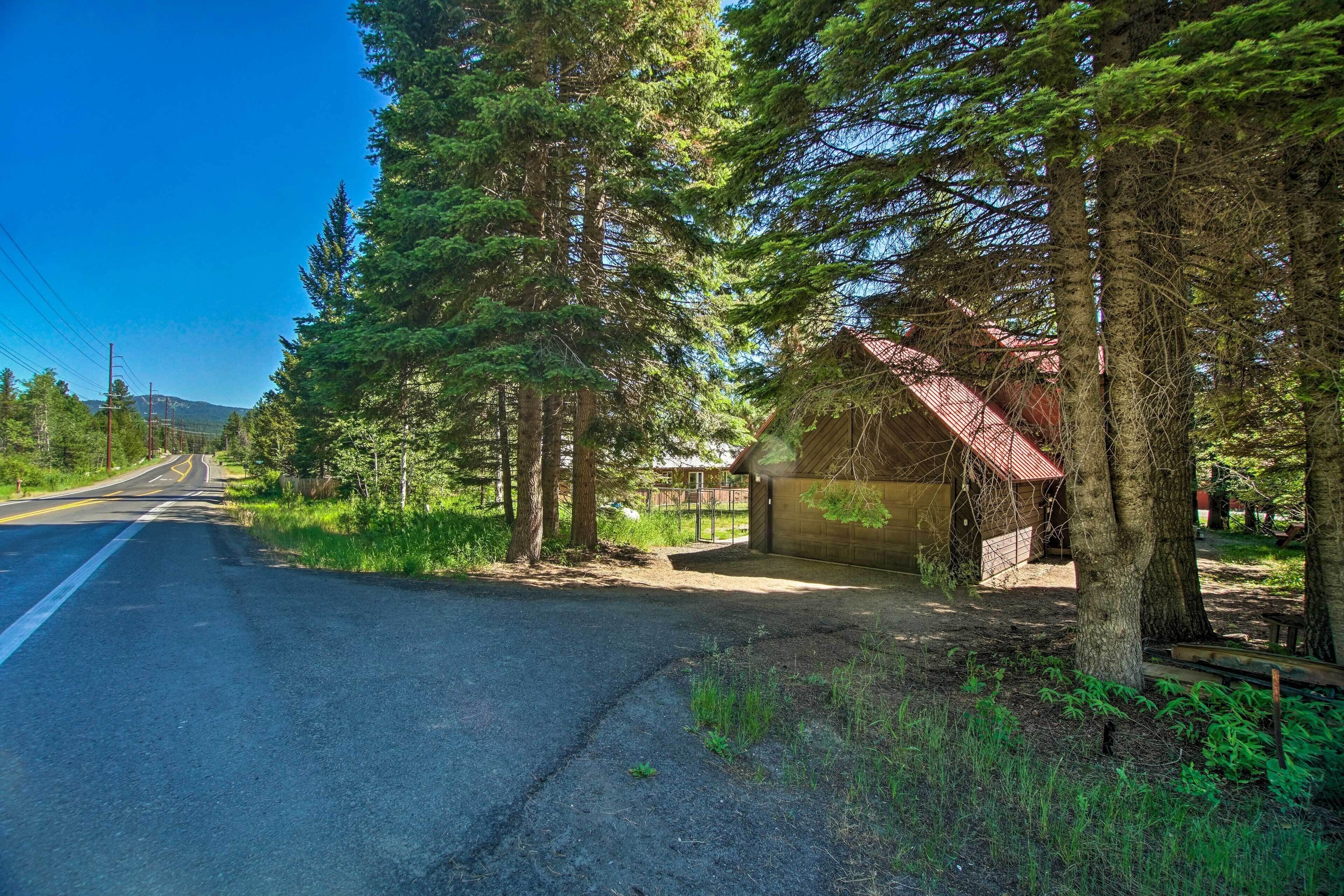 A road with a building on the right, surrounded by trees.