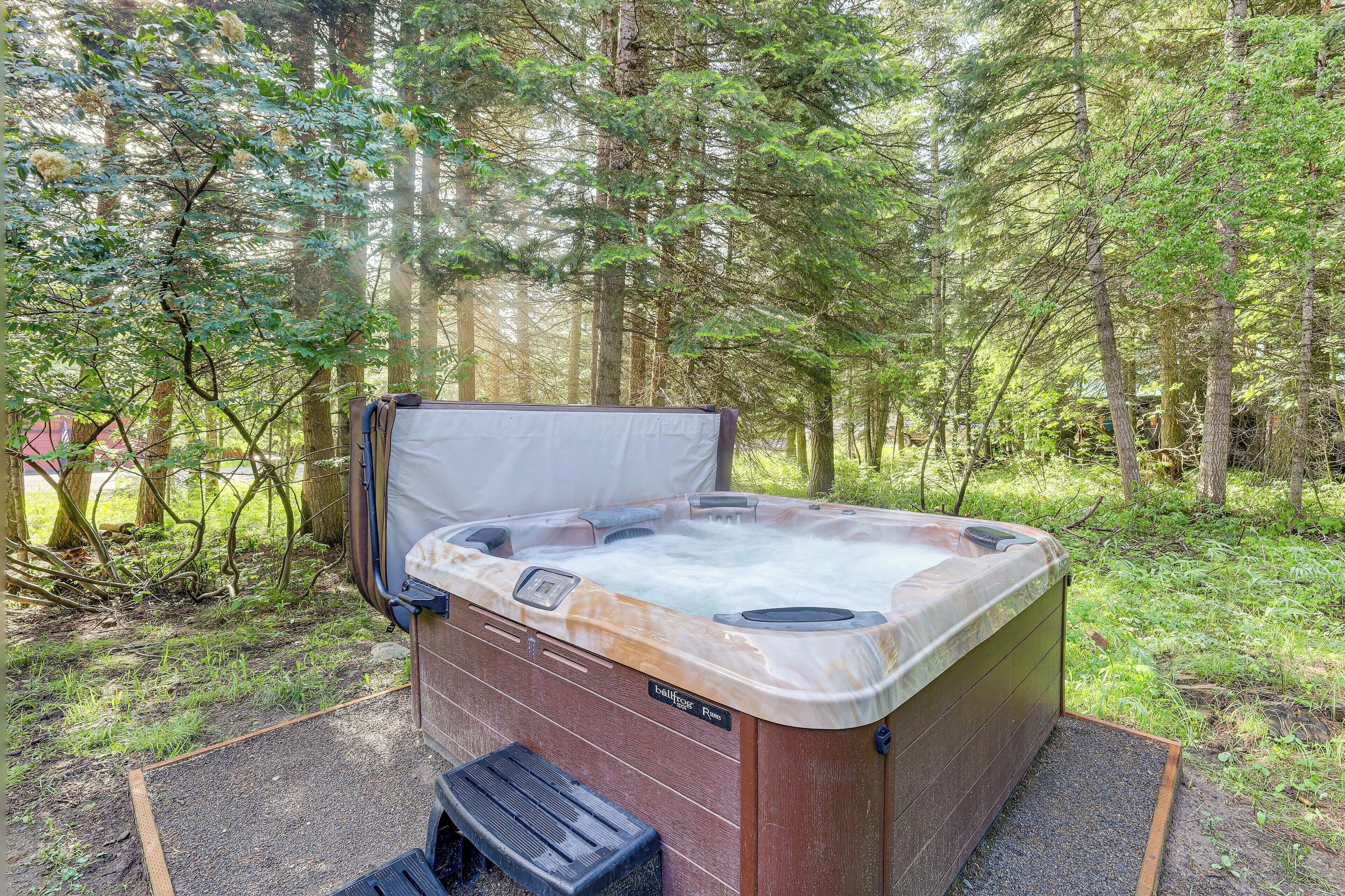 Ein Whirlpool in bewaldeter Landschaft, mit Holzverkleidung und dem Schriftzug 'Bainbridge Spa'.