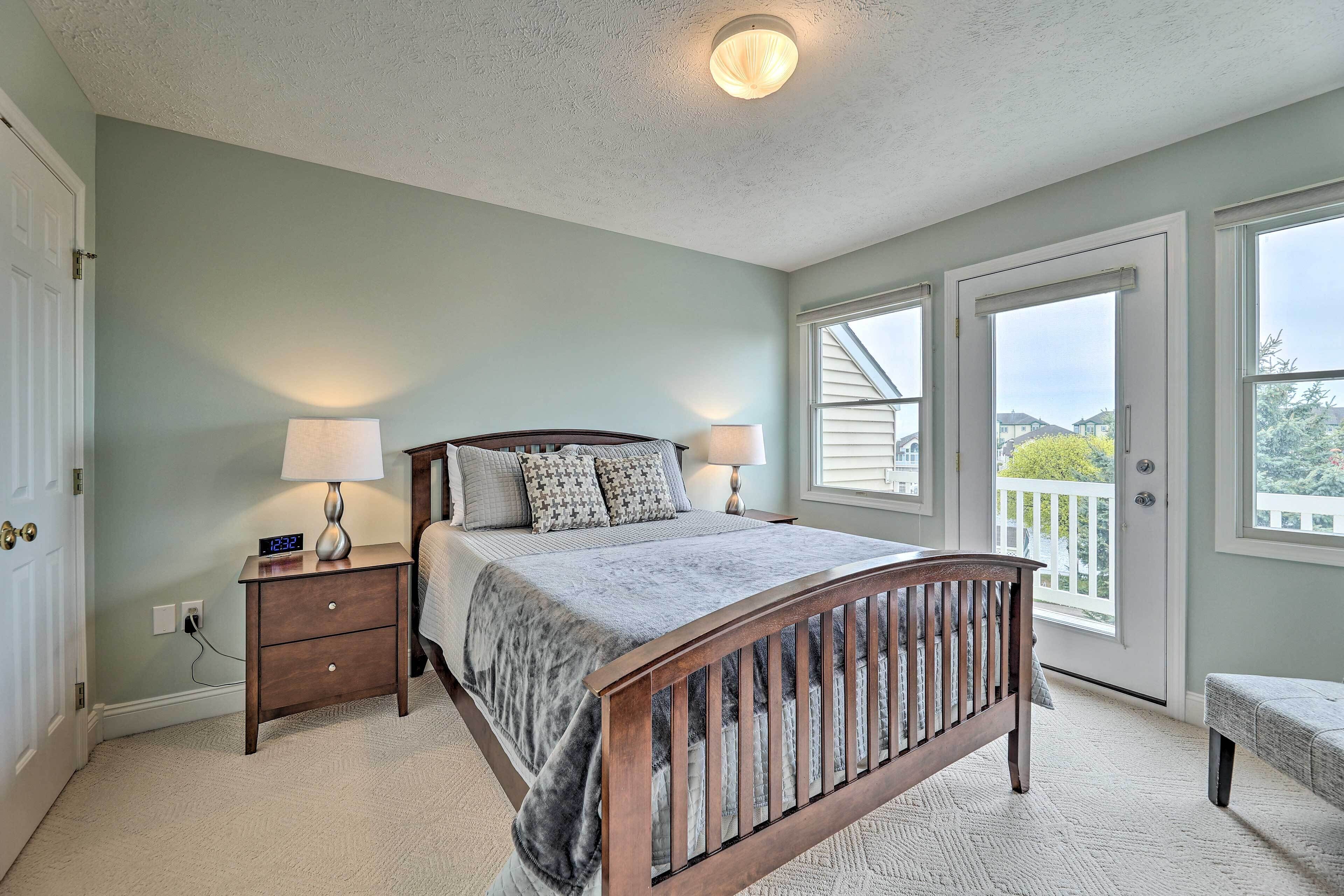 A bedroom with a bed, bedside lamps, a nightstand, a window, and a door.