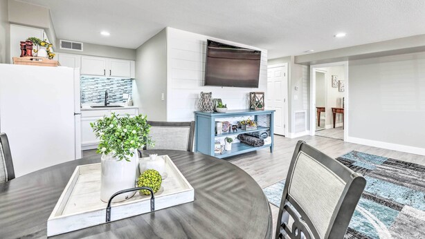 A modern kitchen with white cabinetry, a blue console table, and a dining area with a round table and chairs. - 2 Mi to Dtwn Gilbert! Snowbird Escape w/ Pool (Gilbert)