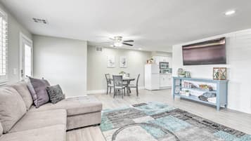 A modern living room with a sectional sofa, a dining area, and a kitchen.