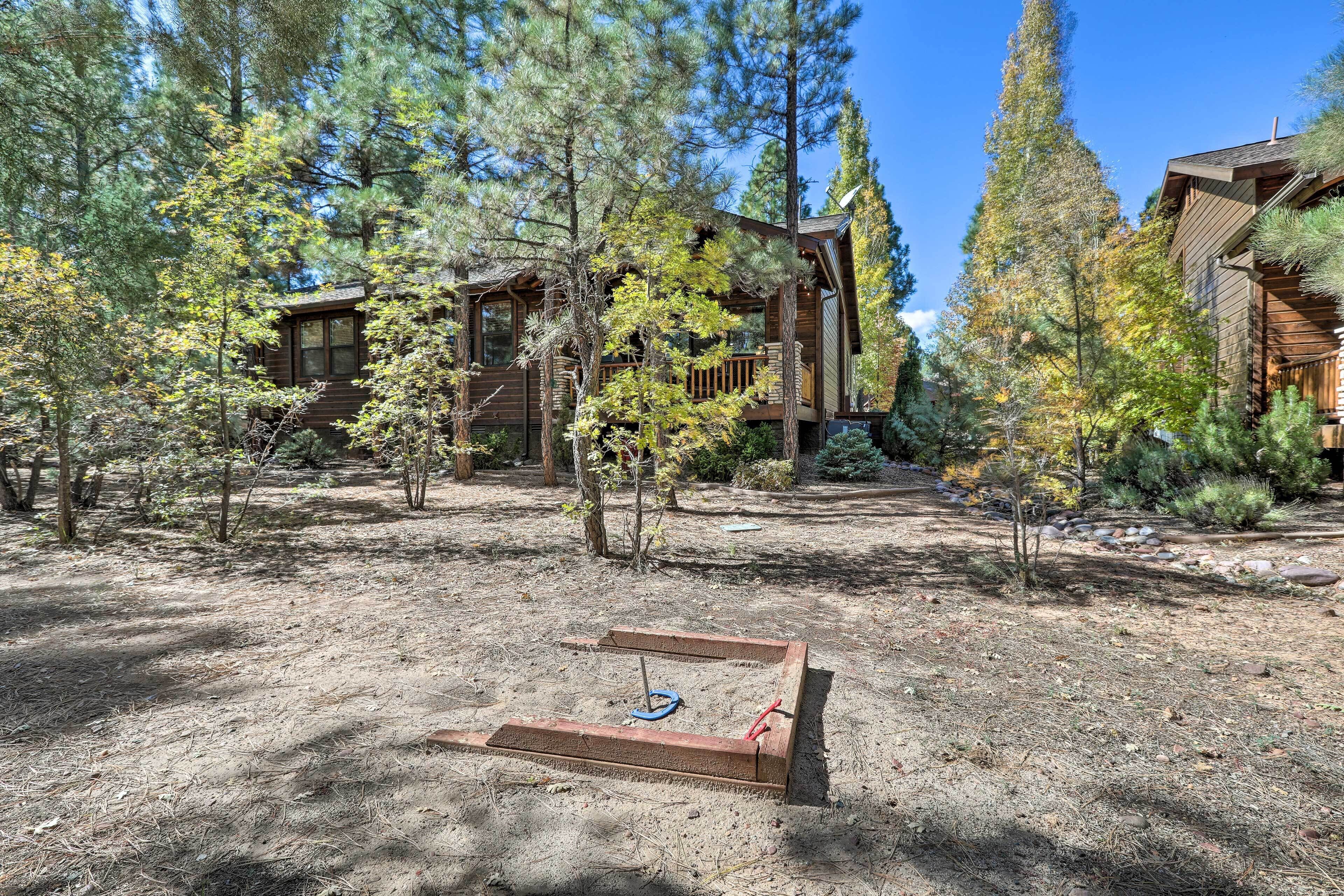 A cabin with a deck, surrounded by trees and a clear sky.