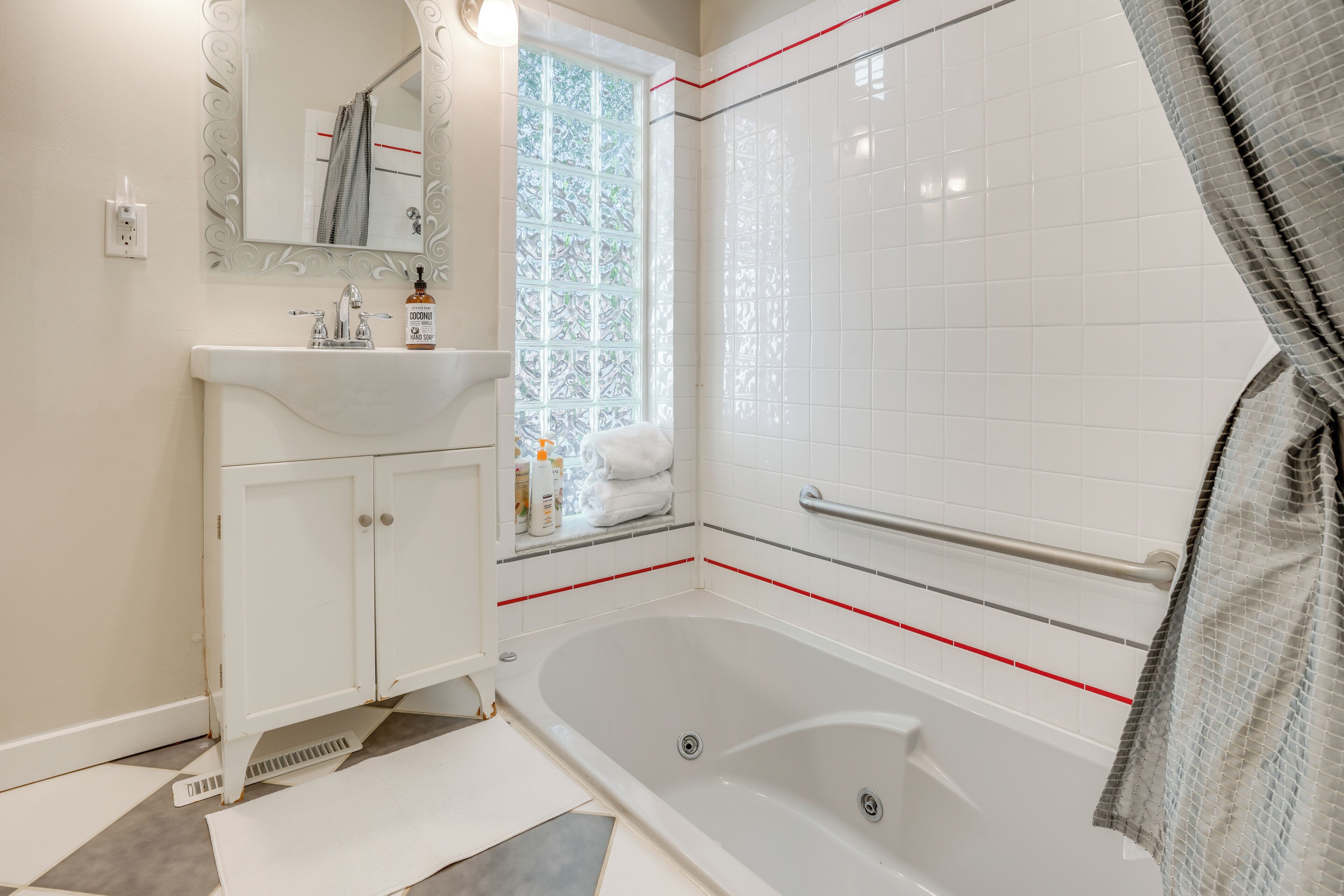 Ein Badezimmer mit weißem Waschbecken, Spiegel und Badewanne.