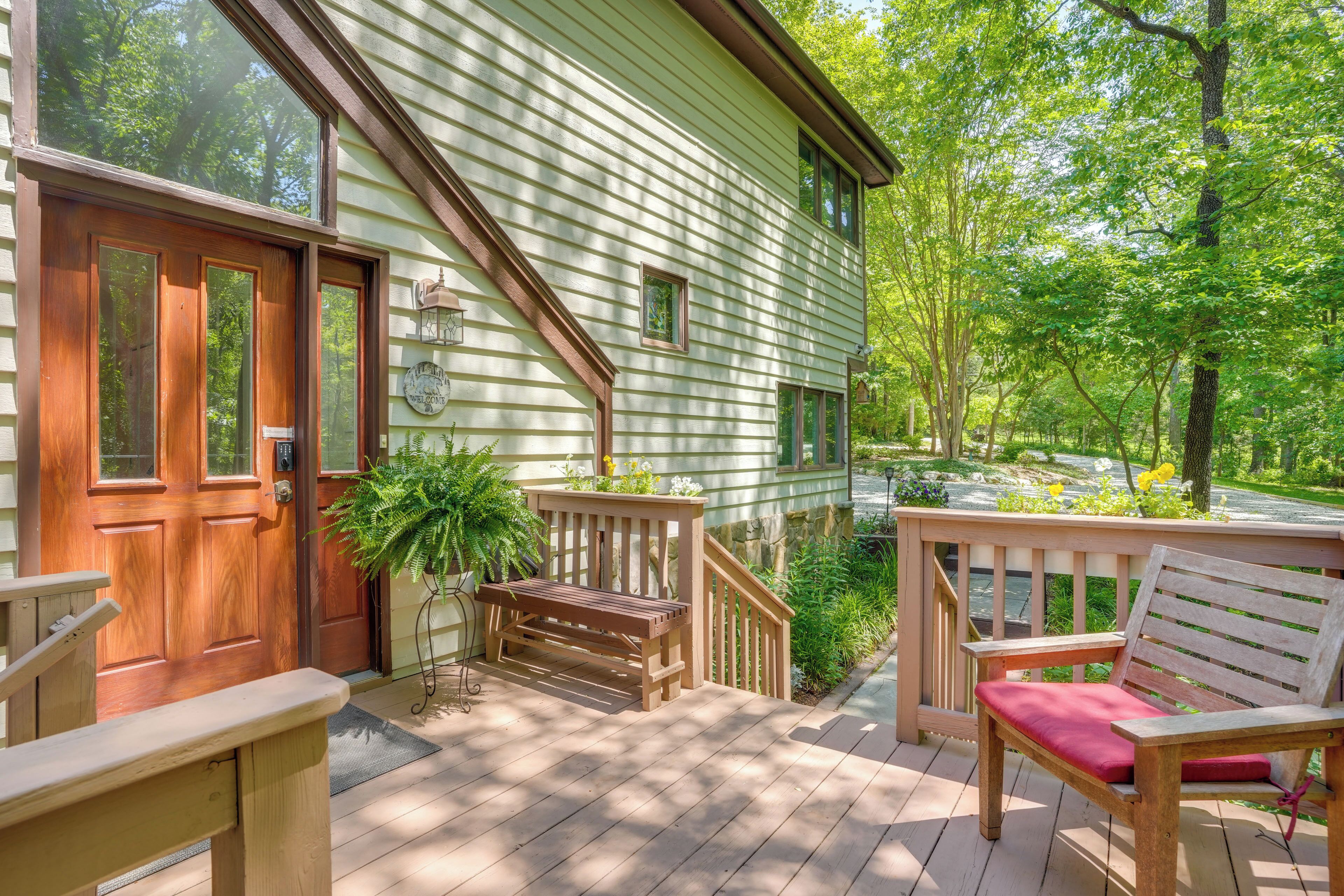 A wooden deck with a bench and a chair, a door, and a small potted plant.