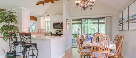 A spacious kitchen with a central island, wooden ceiling beams, and a dining area with a table and chairs.