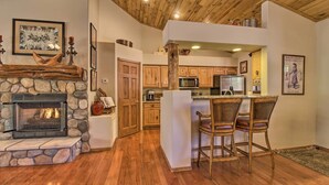 Una cocina con chimenea de piedra, armarios de madera y una barra con taburetes.