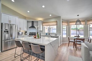 A modern kitchen with a large island, stainless steel appliances, and a dining area with a round table and chairs. - Pool, Putting Green & Furnished Patio: Phoenix Gem (Phoenix)