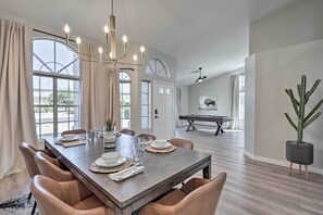 A dining area with a large wooden table set for six, surrounded by leather chairs. A chandelier hangs above, and a pool table is visible in the background. - Pool, Putting Green & Furnished Patio: Phoenix Gem (Phoenix)