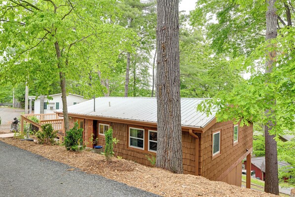 A wooden cabin with a metal roof, surrounded by trees and a well-maintained yard.
