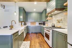 A kitchen with green cabinets, a white countertop, and a wooden floor. - Hot Tub & Lake Access at Poconos Getaway! (Lake Ariel)