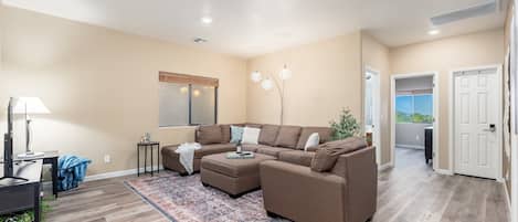 A modern living room with a sectional sofa, a coffee table, and a patterned rug.