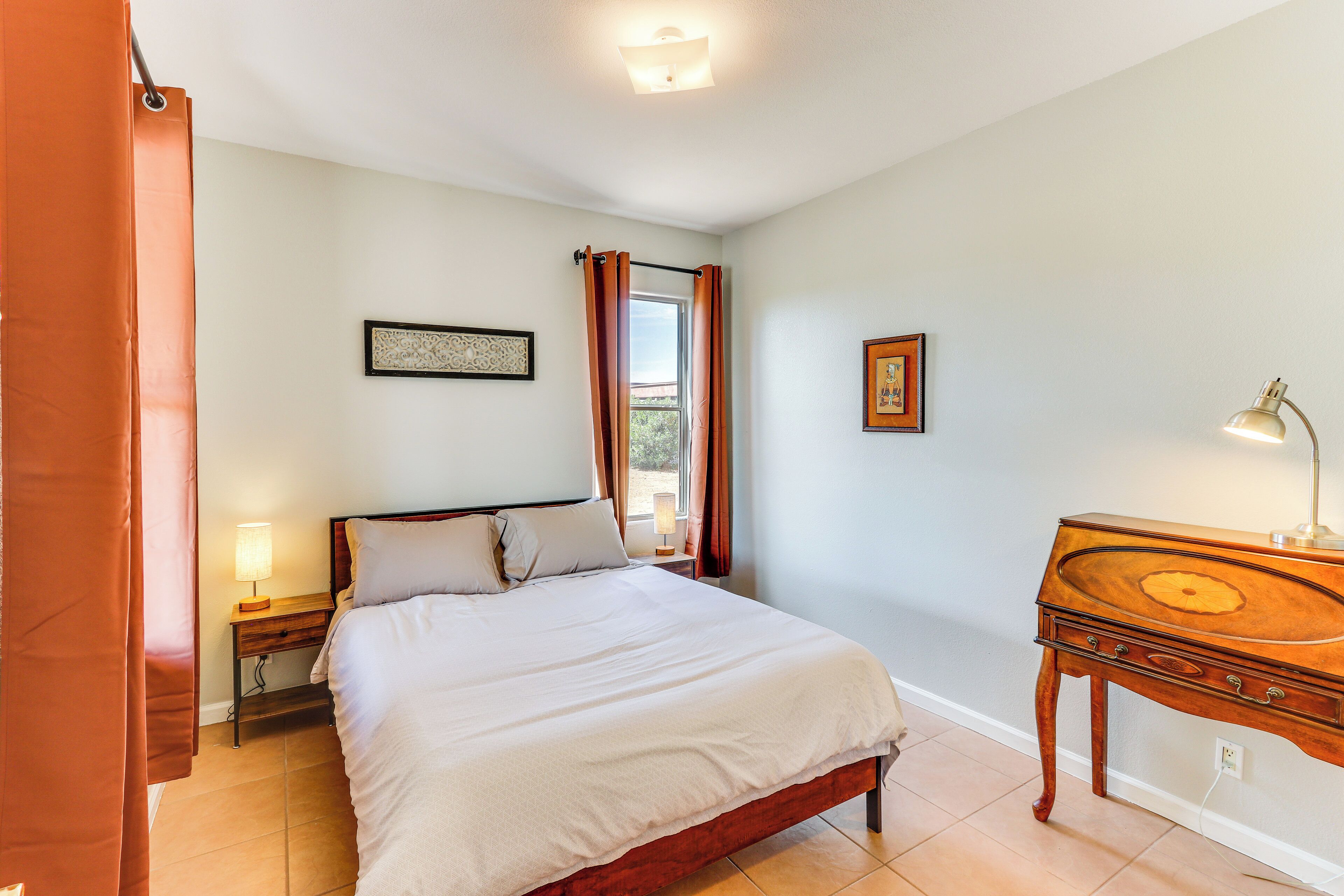 Un dormitorio con cama, mesita de noche, lámpara y cómoda de madera.