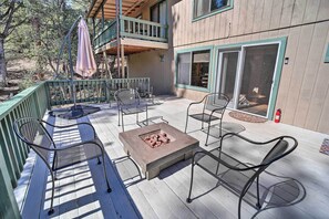 Eine Holzterrasse mit Sitzgelegenheiten im Freien, einer Feuerstelle und einem überdachten Bereich mit einem Balkon.