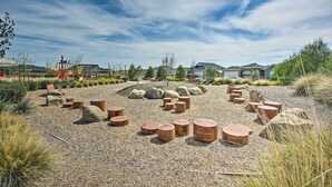 Un espacio al aire libre con suelo de grava, rocas dispersas y taburetes de madera.