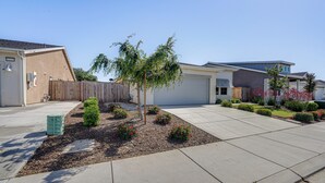 Zona residencial con entrada pavimentada, un árbol pequeño y valla de madera.