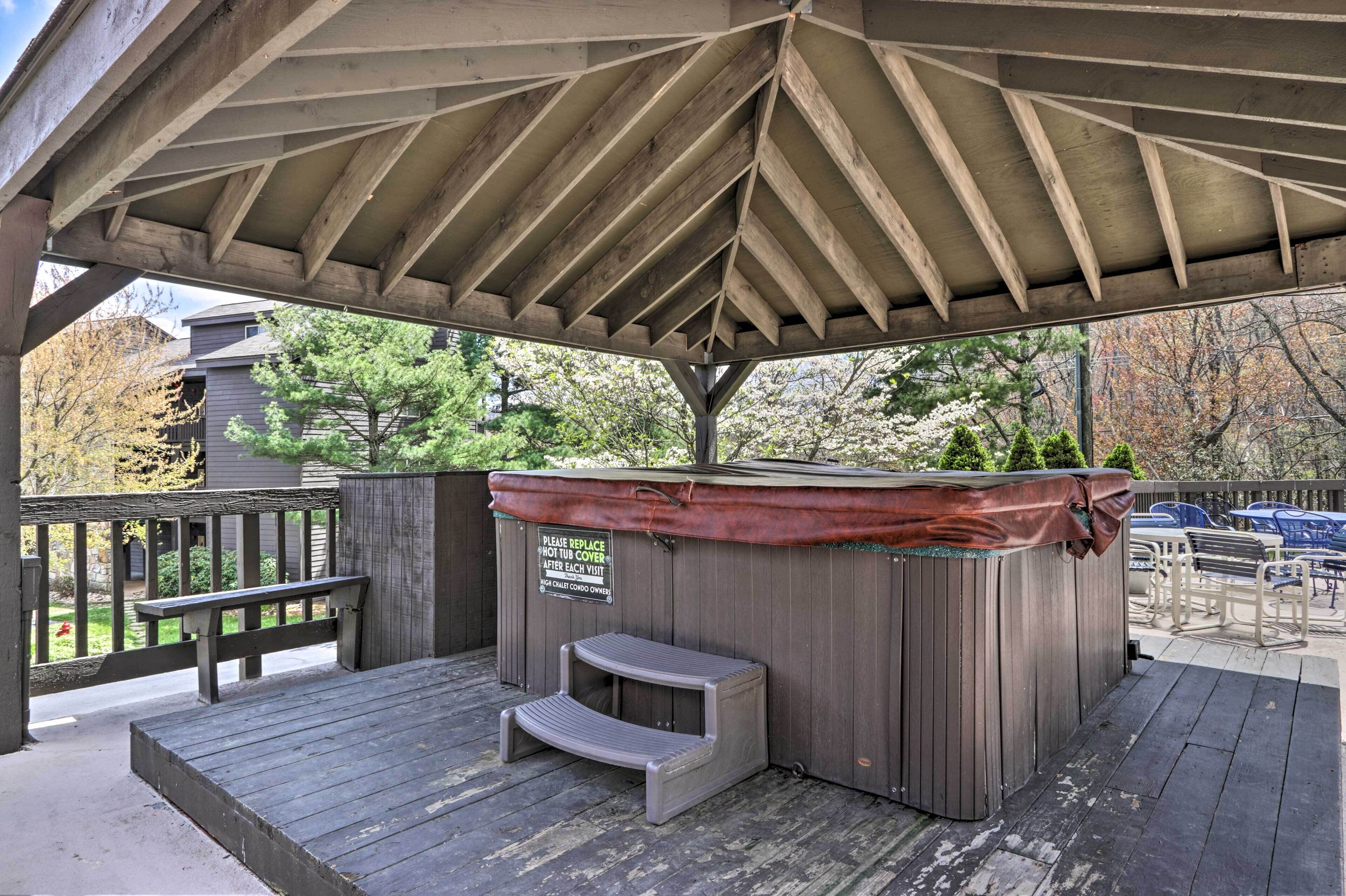 A covered outdoor area with a hot tub, wooden deck, and seating.