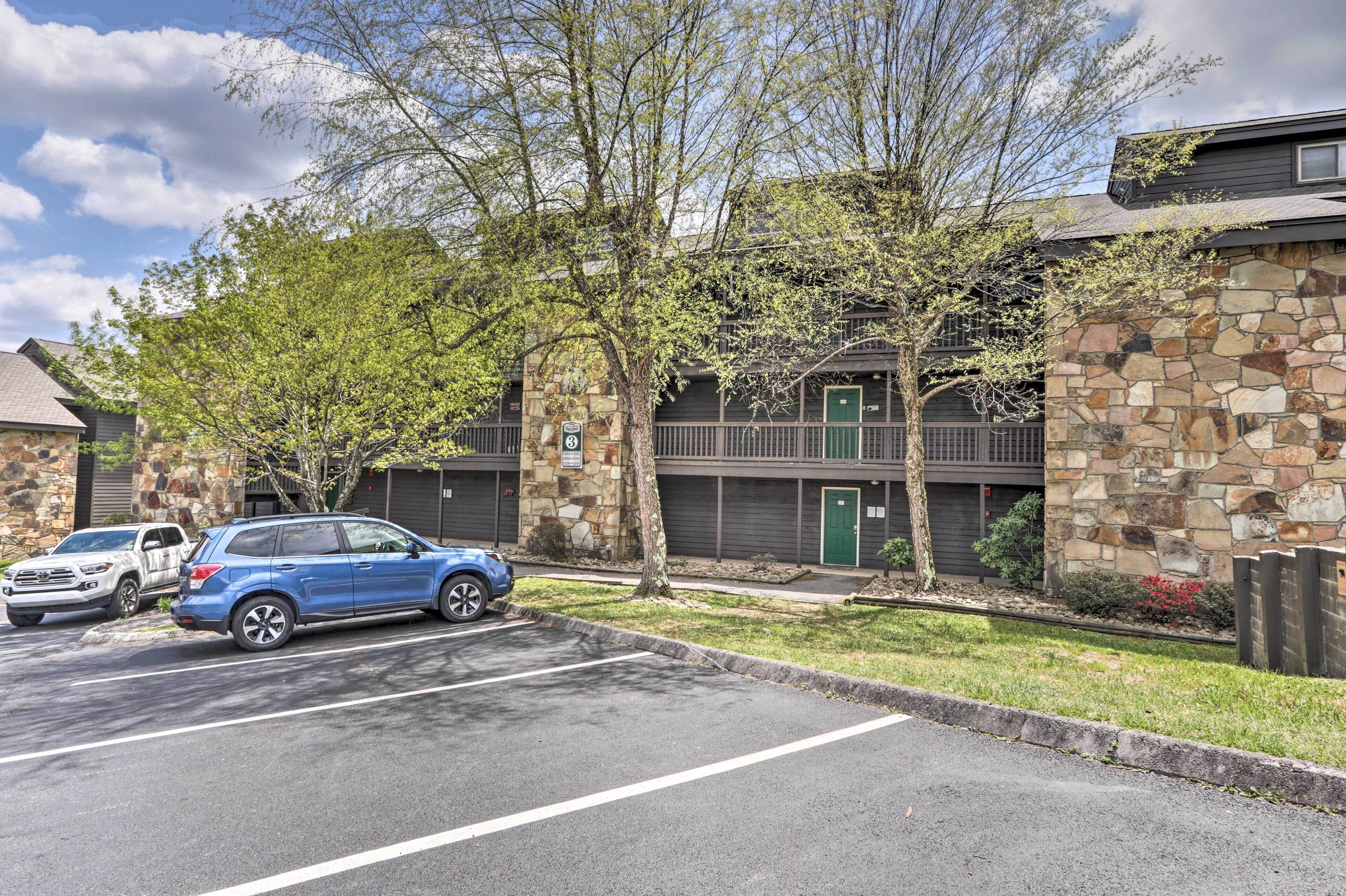 A multi-story building with stone facade, parking lot, and trees.