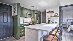 A modern kitchen with green cabinets, a large island, and a bar area with stools.