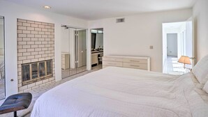Quarto com uma cama grande, um banco, uma lareira, um guarda-roupa e um banheiro visível por uma porta aberta.